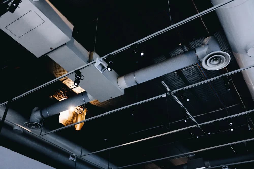 Overhead ductwork and air vents running across a dark ceiling